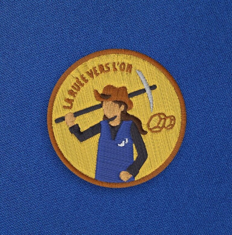 Broderie femme jaune du visuel La ruée vers l'or sur fond bleu.