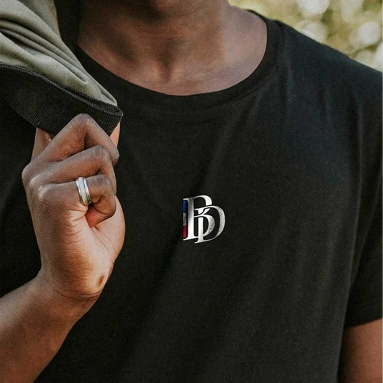 T-shirt noir Barber District porté avec logo monogramme sur la poitrine.