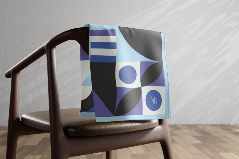 Carré de soie Maison Gabrielle à motif géométrique bleu et violet posé sur une chaise.