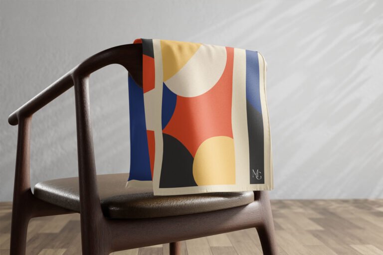 Carré de soie Maison Gabrielle à motif jaune, noir et bleu posé sur une chaise.