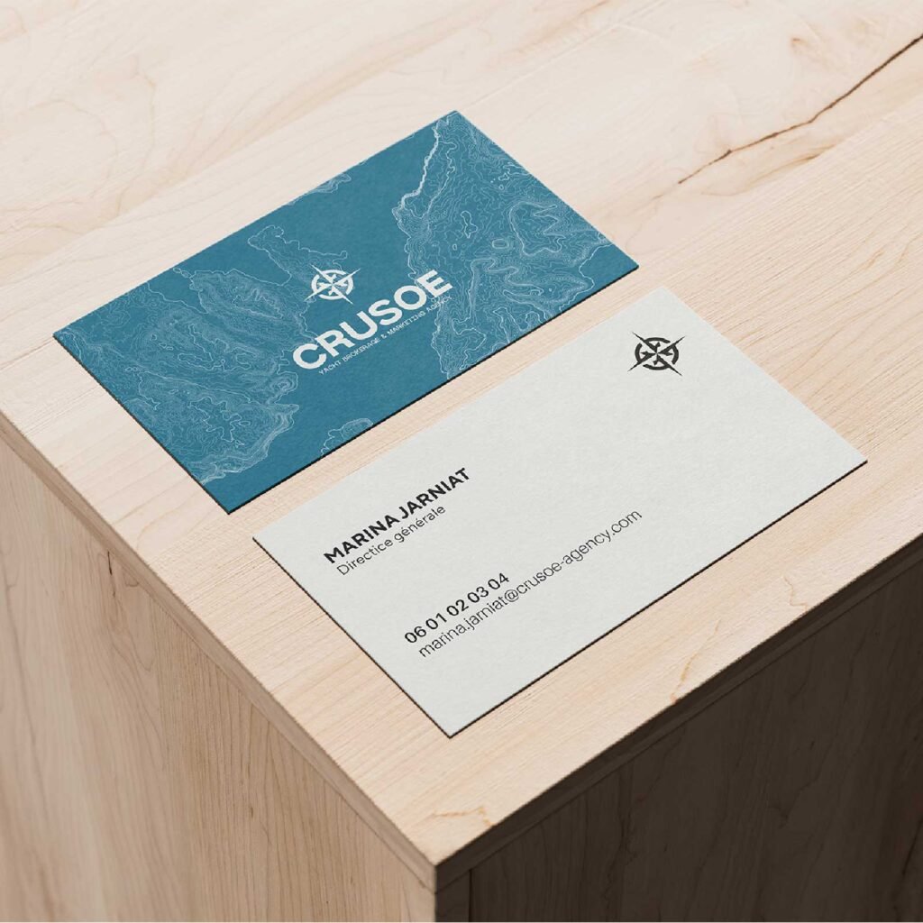 Cartes de visite Crusoe posées sur un support en bois.