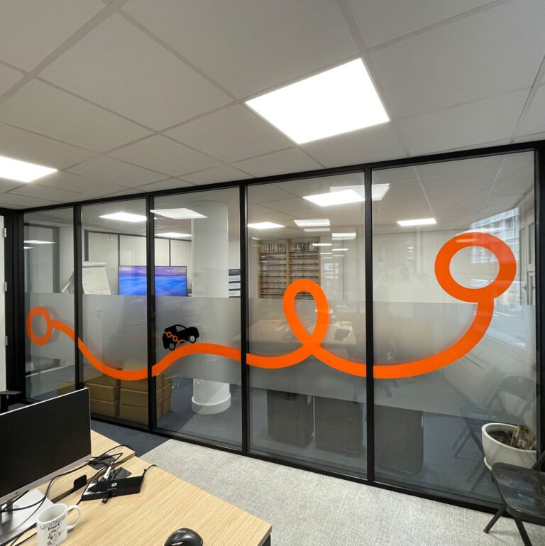 Espace de bureau vitré avec tracé graphique orange sur les vitres.